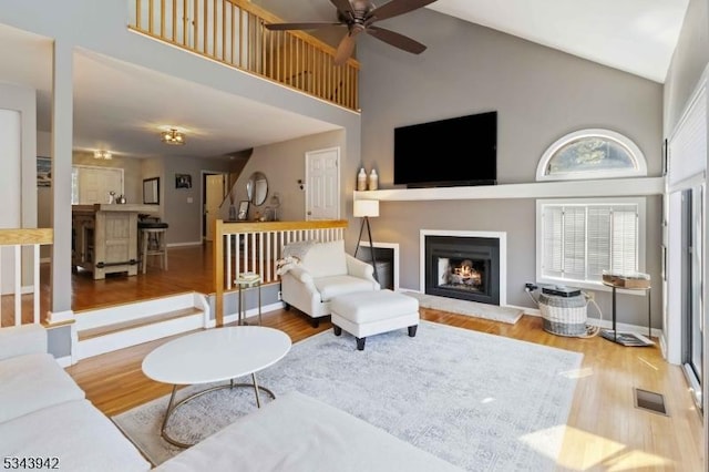 living area featuring high vaulted ceiling, wood finished floors, visible vents, and ceiling fan