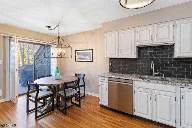 kitchen featuring tasteful backsplash, light wood-type flooring, stainless steel dishwasher, an inviting chandelier, and a sink