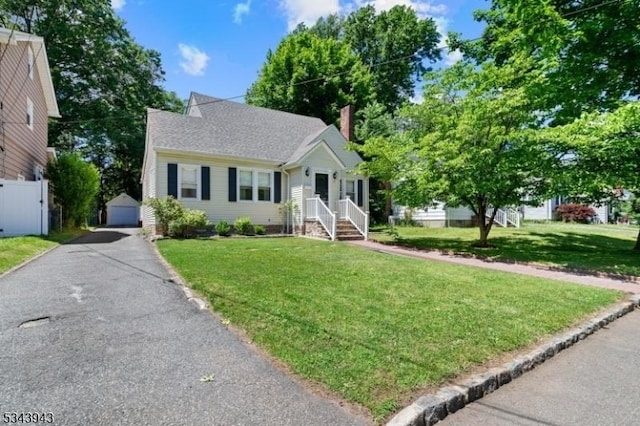 view of front of property with a front yard, fence, an outbuilding, and a chimney