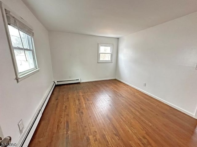 empty room with a baseboard radiator, baseboards, and wood finished floors