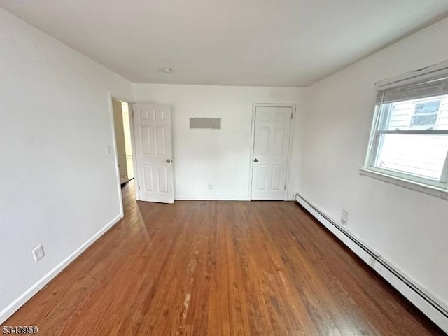 spare room featuring baseboards, baseboard heating, and wood finished floors