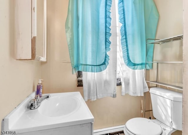 half bath featuring baseboard heating, vanity, and toilet