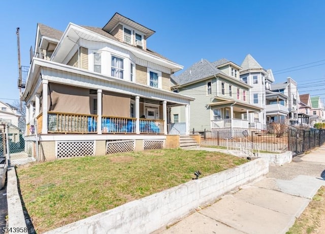 american foursquare style home with a front lawn, fence, and covered porch