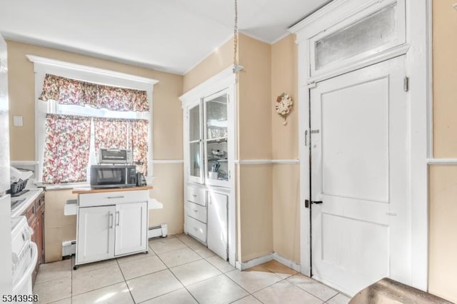 kitchen with light tile patterned floors, stainless steel microwave, and a baseboard radiator