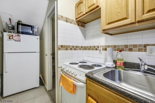 kitchen with a sink, dark countertops, tasteful backsplash, white appliances, and light tile patterned flooring