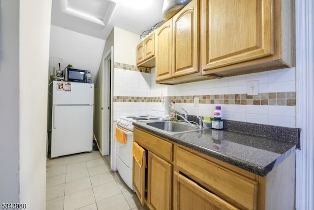 kitchen with white appliances, light tile patterned flooring, a sink, dark countertops, and backsplash