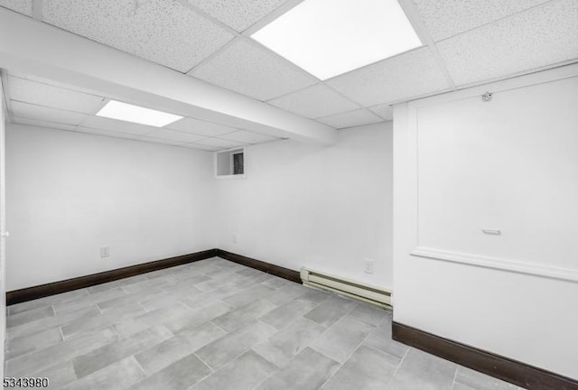 finished basement featuring a baseboard heating unit, visible vents, baseboards, and a drop ceiling