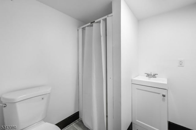 bathroom with walk in shower, toilet, and a sink