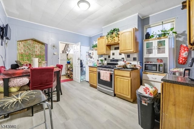 kitchen with ornamental molding, tasteful backsplash, dark countertops, appliances with stainless steel finishes, and light wood finished floors