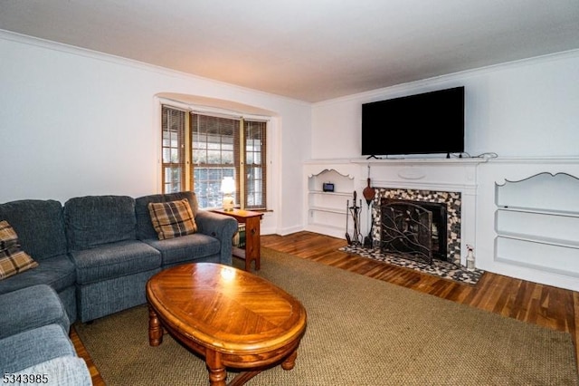 living area with wood finished floors, ornamental molding, and a fireplace