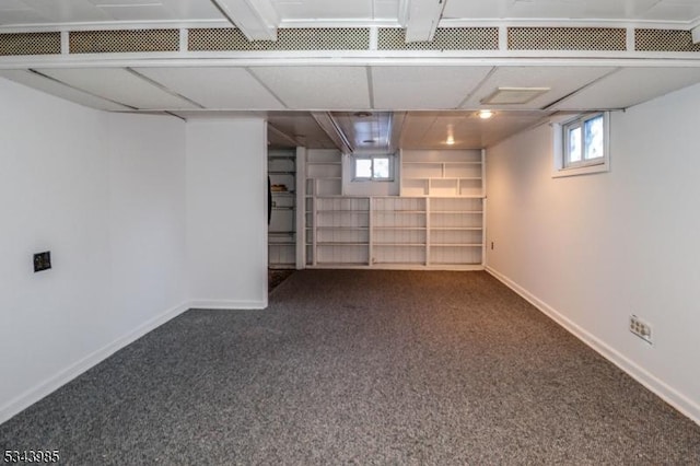 basement featuring baseboards and dark carpet