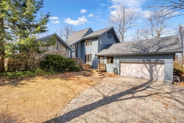 view of front of home with a garage, roof with shingles, and dirt driveway