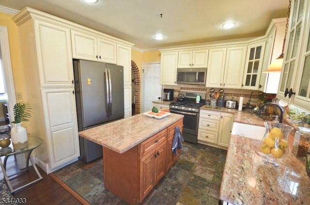 kitchen with a sink, tasteful backsplash, a center island, appliances with stainless steel finishes, and light stone countertops