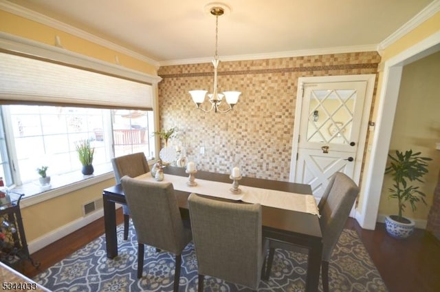 dining room featuring a chandelier, crown molding, baseboards, and wood finished floors