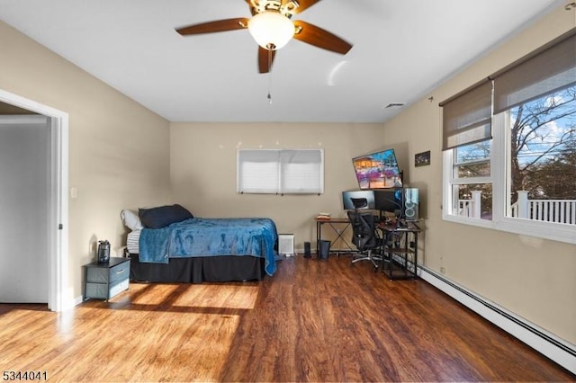 bedroom featuring a baseboard radiator, baseboards, and wood finished floors