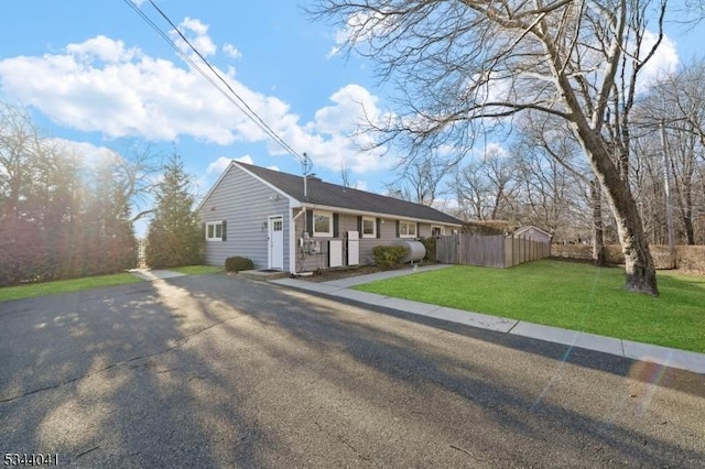 single story home with heating fuel, a front lawn, and fence