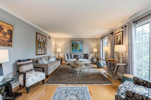 living room featuring a wealth of natural light, crown molding, and light wood-style floors