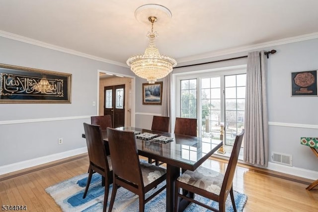 dining area featuring an inviting chandelier, crown molding, light wood-style floors, and visible vents