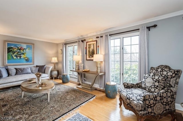 living area with baseboards, wood finished floors, and ornamental molding