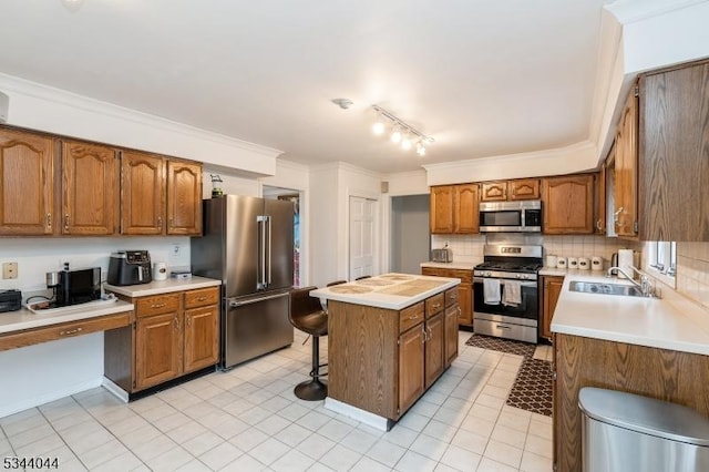 kitchen featuring a center island, crown molding, appliances with stainless steel finishes, a kitchen breakfast bar, and a sink