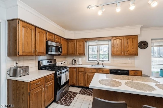 kitchen with crown molding, light countertops, a wealth of natural light, appliances with stainless steel finishes, and a sink