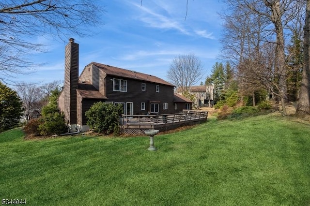 back of property featuring a lawn, a chimney, and a deck