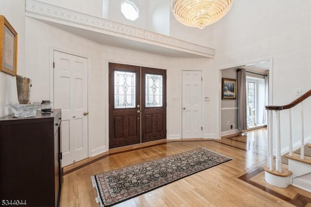 entryway with stairway, baseboards, a high ceiling, and wood finished floors