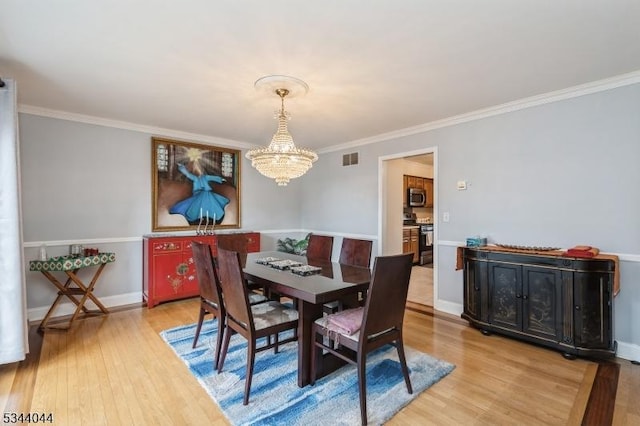 dining area featuring a chandelier, visible vents, crown molding, and light wood-style floors