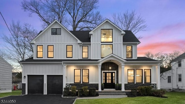 modern farmhouse with board and batten siding, aphalt driveway, french doors, stone siding, and an attached garage