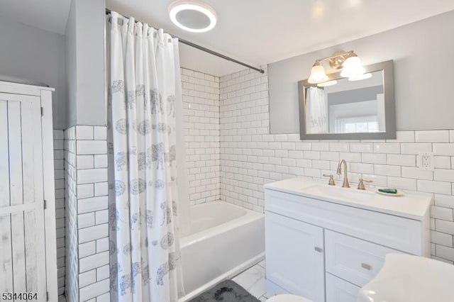 full bathroom featuring shower / bathtub combination with curtain, marble finish floor, tile walls, and vanity