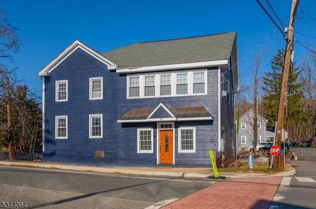 view of front of house featuring metal roof, a standing seam roof, and fence