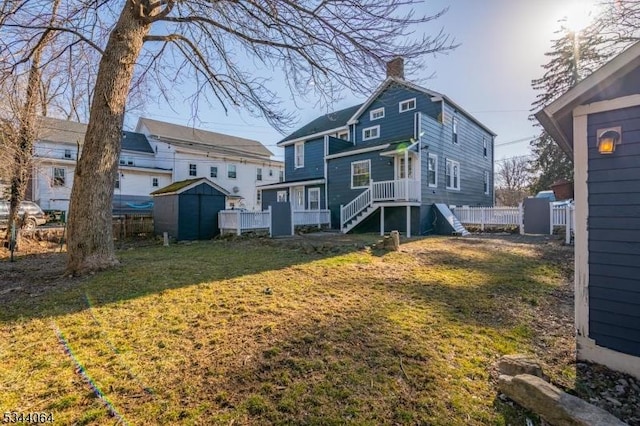 rear view of property featuring an outbuilding, a lawn, a chimney, and fence