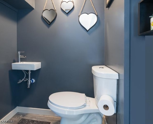 half bath with a sink, baseboards, and toilet