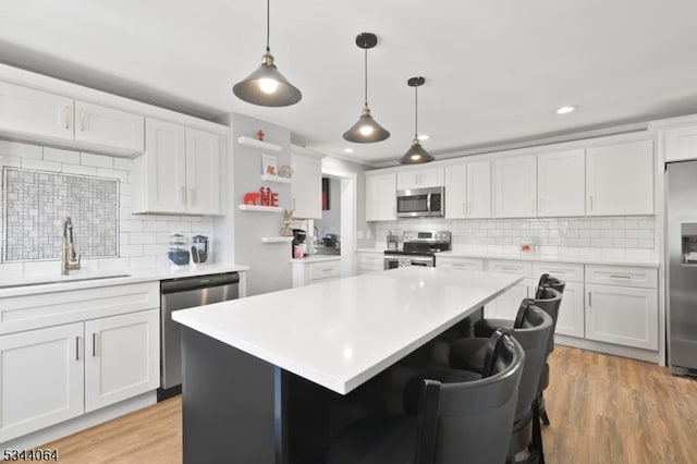 kitchen with a sink, open shelves, stainless steel appliances, white cabinets, and light countertops