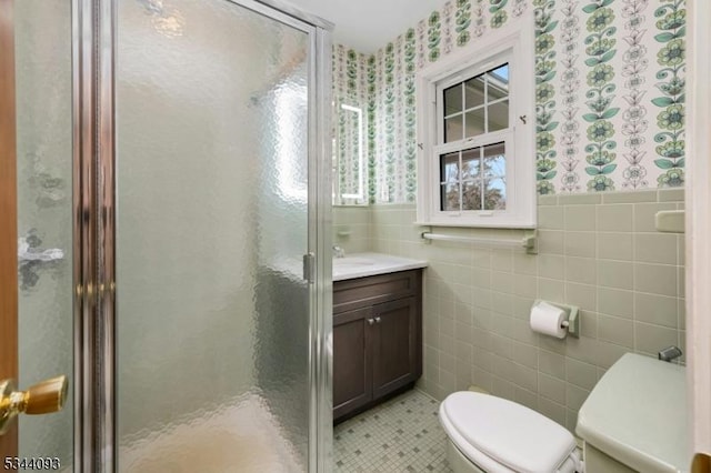 bathroom featuring wallpapered walls, a shower stall, toilet, and tile walls