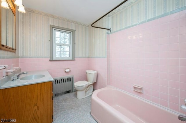 bathroom featuring radiator, wallpapered walls, wainscoting, tile walls, and toilet