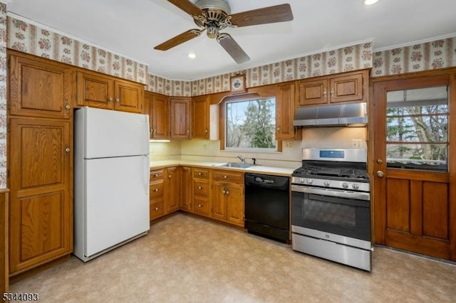 kitchen featuring wallpapered walls, under cabinet range hood, dishwasher, freestanding refrigerator, and stainless steel gas stove