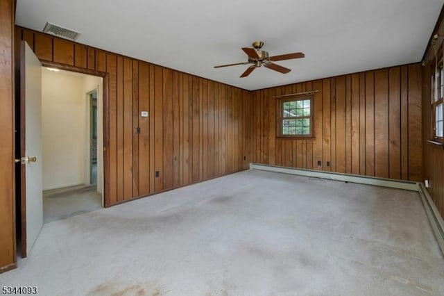 spare room featuring wooden walls, visible vents, carpet, ceiling fan, and baseboard heating