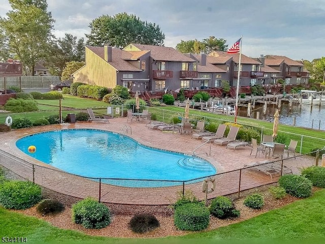 pool with a residential view, a lawn, a patio, and fence