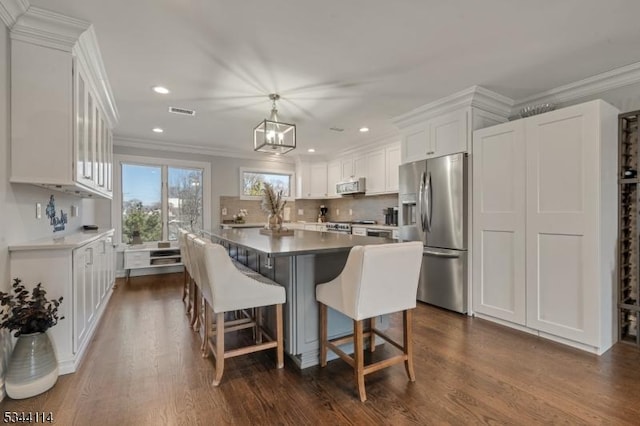 kitchen with visible vents, white cabinets, stainless steel appliances, and ornamental molding