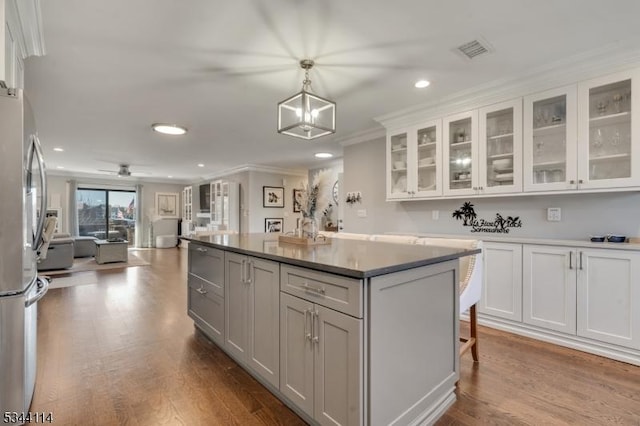 kitchen with visible vents, a kitchen island, open floor plan, ornamental molding, and freestanding refrigerator