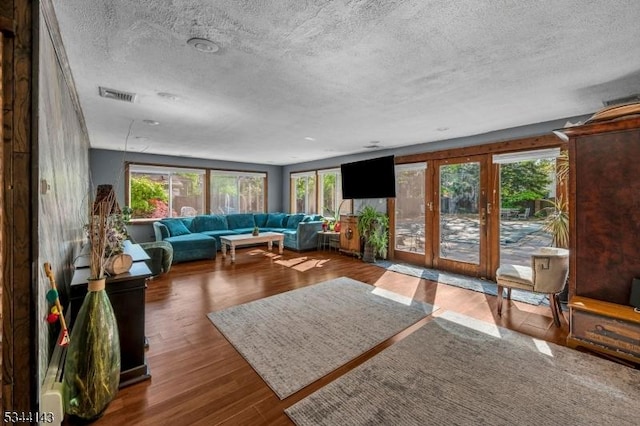 living area with plenty of natural light, a textured ceiling, and wood finished floors