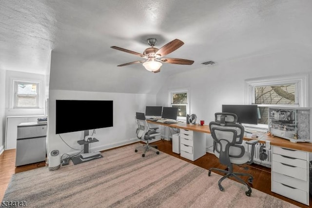 office area with visible vents, wood finished floors, vaulted ceiling, and a healthy amount of sunlight