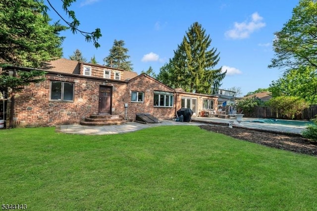 back of house with a lawn, brick siding, fence, and a patio area