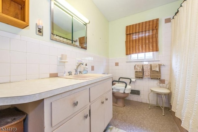 full bath with tile walls, a wainscoted wall, toilet, vanity, and visible vents