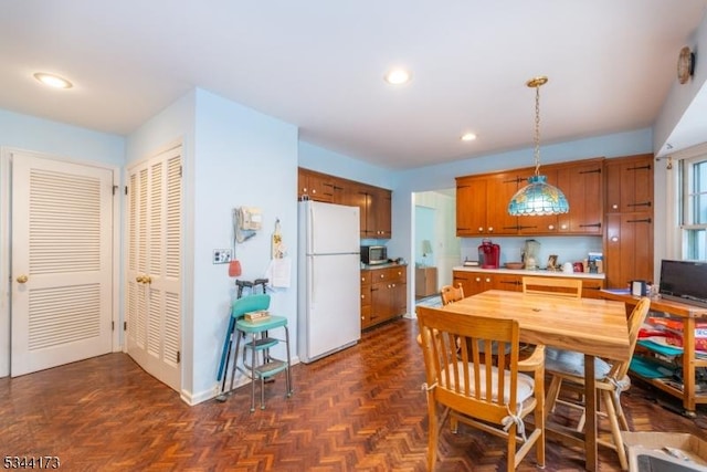 kitchen featuring stainless steel microwave, recessed lighting, brown cabinetry, hanging light fixtures, and freestanding refrigerator