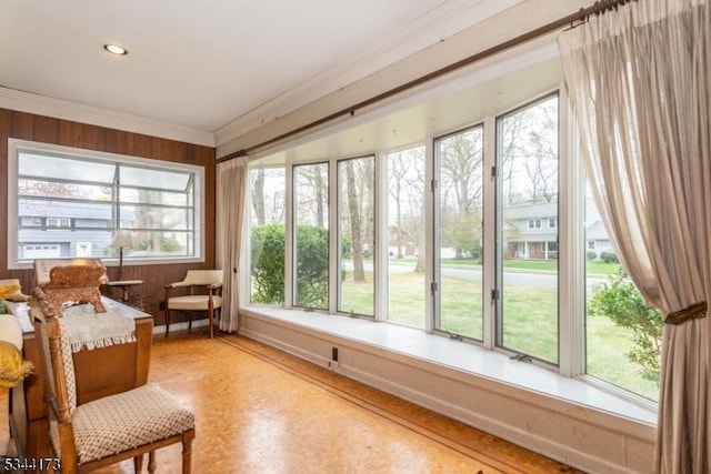 sunroom with crown molding and wood walls