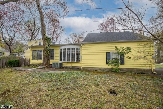 back of property with cooling unit, a yard, and fence