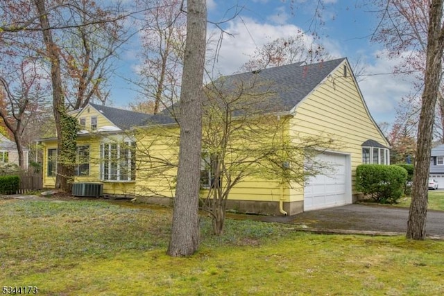 view of side of home featuring a lawn, central AC, and aphalt driveway