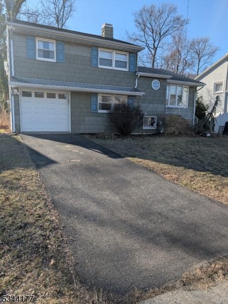 view of front of home with a garage, driveway, and a chimney